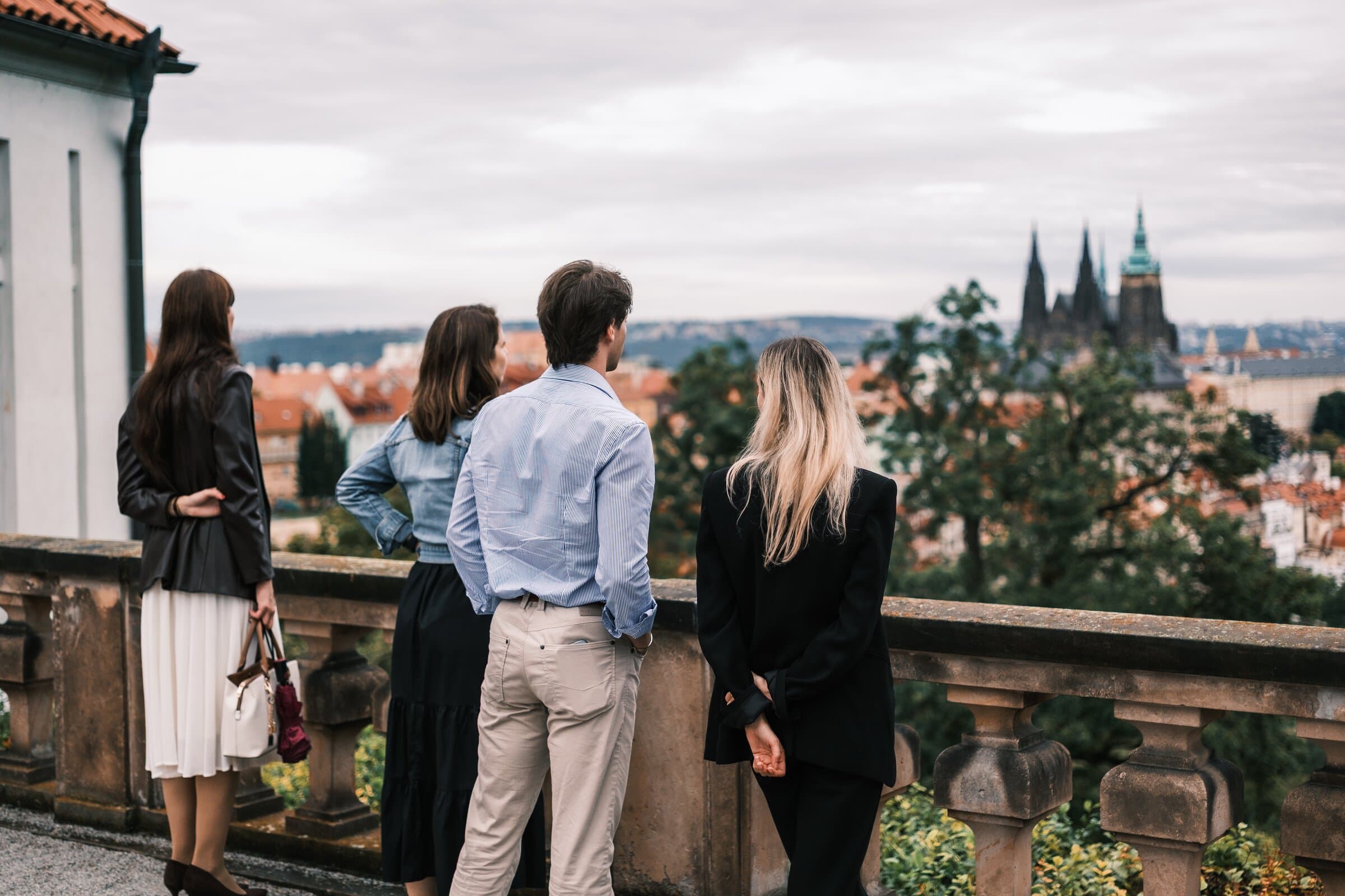 Four guests on a stone terrace looking across red roofs to the cathedral spires