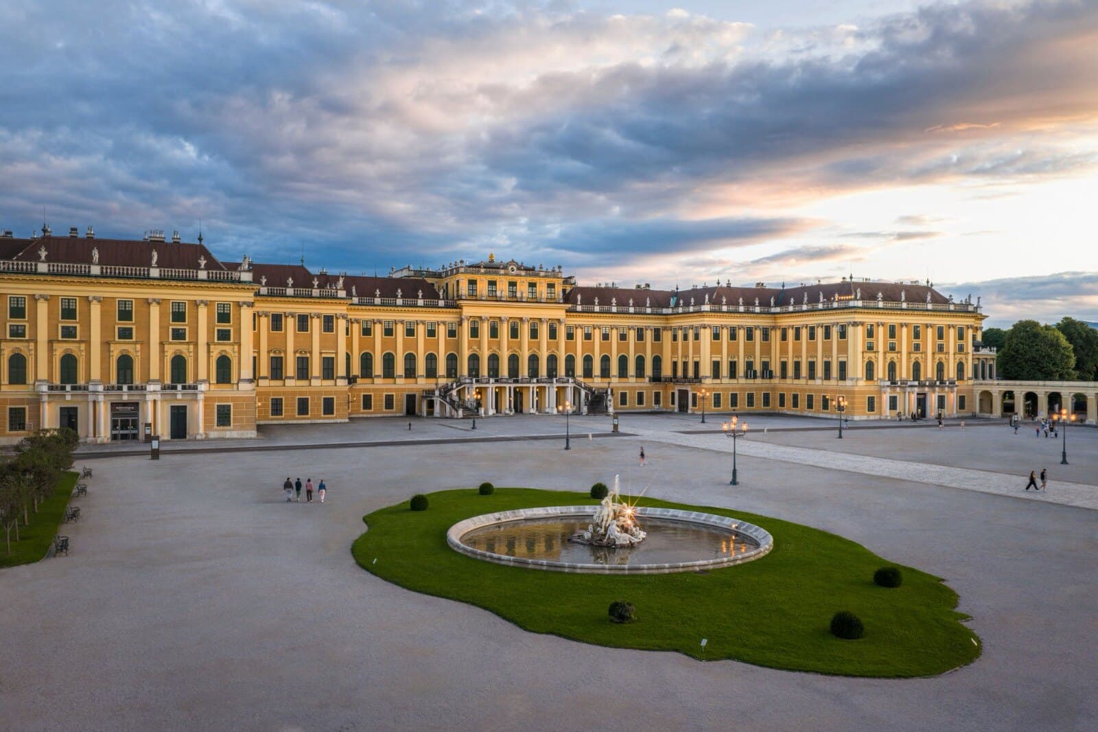 Schönbrunn Palace and its fountain at dusk, the courtyard almost empty