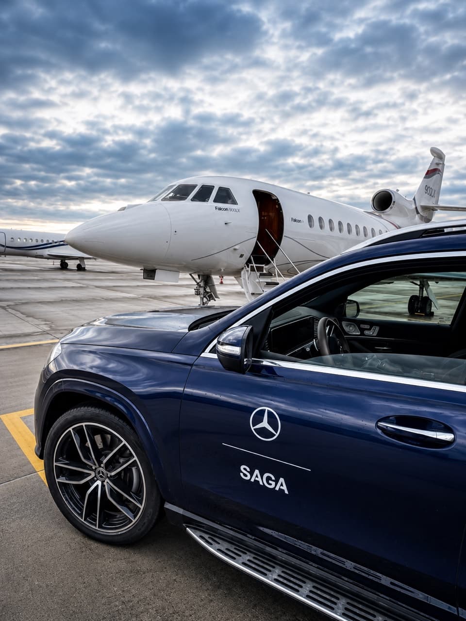 Navy Mercedes SUV waiting beside a Falcon 900LX private jet on the tarmac